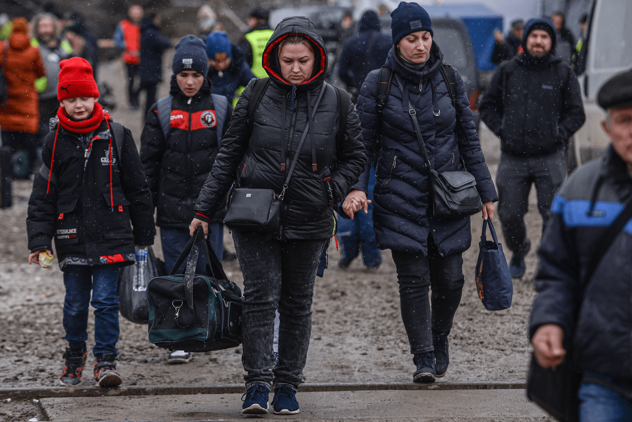 PEOPLE-WHO-FLED-THE-WAR-IN-UKRAINE-WALK-TOWARDS-A-BUS-TO-RELOCATE-THEM-ACROSS-POLAND-AFTER-CROSSING-THE-POLISH-UKRAINIAN-BORDER
